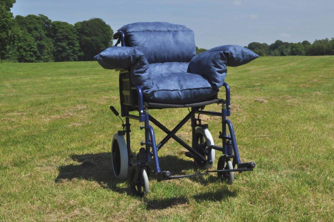 a blue chair with two pillows on it in a field